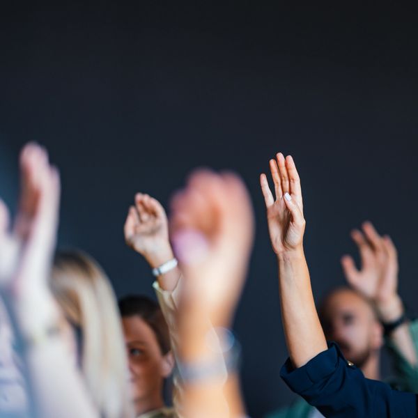 People raising their hands in a meeting or classroom.