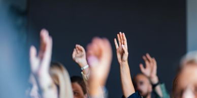 People raising their hands in a meeting or event.