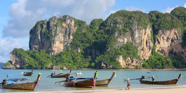Boats on a beach with cliffs in the background.