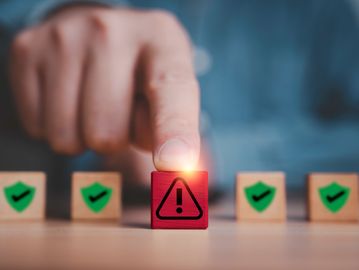 Finger pressing a red block with an exclamation mark, surrounded by green checkmark blocks.