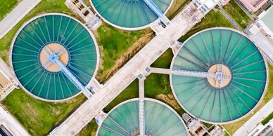 Aerial view of circular water treatment tanks with blue structures and green grass.
