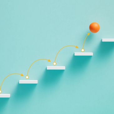 A rising set of white steps with an orange ball moving upward to show progress