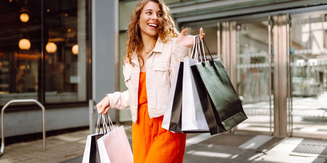 Happy woman carrying multiple shopping bags outdoors.