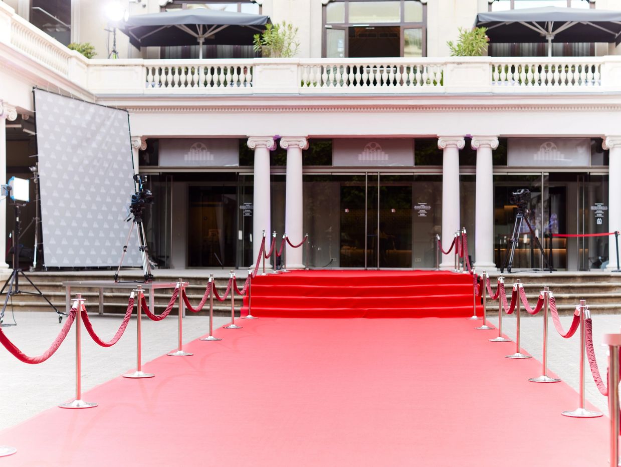 Empty red carpet entrance with ropes and lighting setup.
