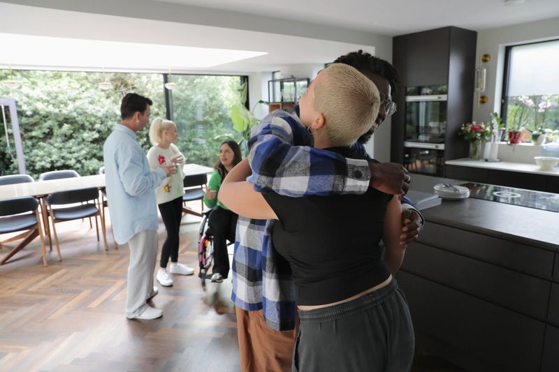 Diverse group of friends talking and hugging during meeting at home