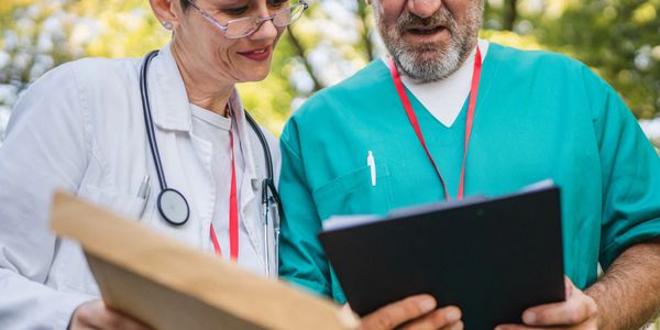 Two doctors reviewing medical documents outdoors.