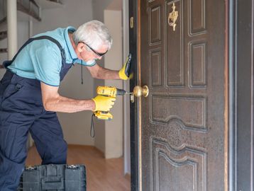 Man using drill to fix door lock.