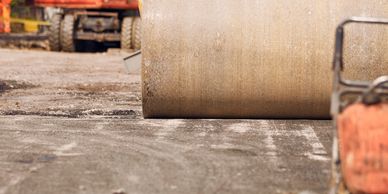 Close-up of a road roller compacting asphalt at a construction site.