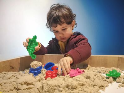 A child playing in a sandtray as they would in a play therapy session.