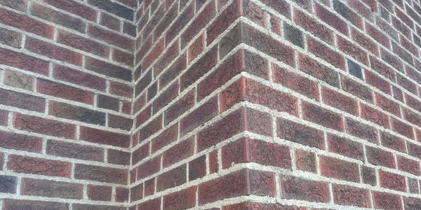 Close-up of a red brick wall corner with white mortar.