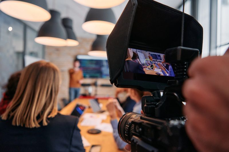 A videographer captures the essence of a business meeting in a modern office, skillfully documenting corporate dynamics and collaboration.