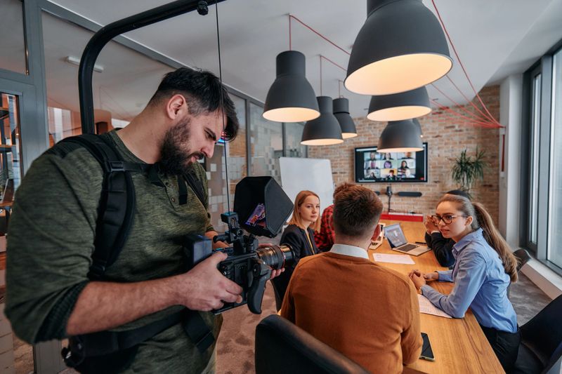 A videographer captures the essence of a business meeting in a modern office, skillfully documenting corporate dynamics and collaboration.