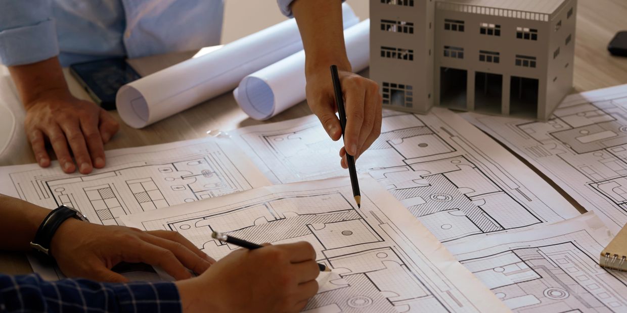 Two people reviewing architectural blueprints on a desk.