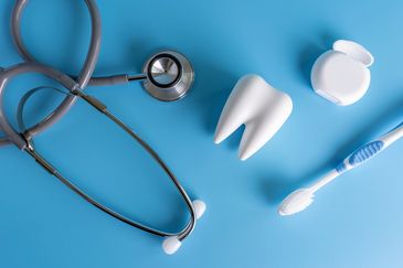 Dental health tools including a stethoscope, tooth model, dental floss, and toothbrush on blue.