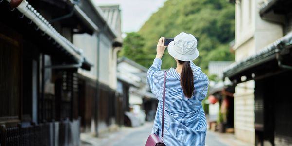 Woman taking photo on a quiet street lined with traditional buildings.