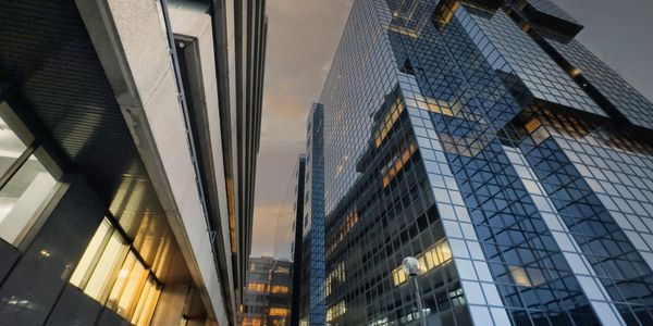 Modern glass skyscrapers reflecting city lights at dusk.
