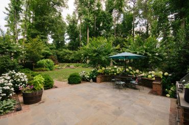 Lush garden with patio seating and umbrella.