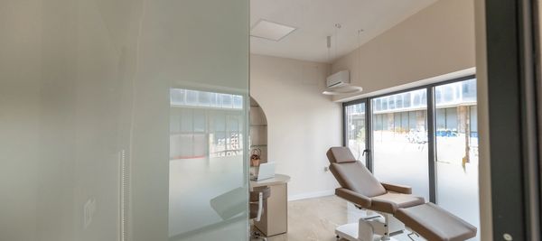 Modern medical examination room with reclining chair and large windows.