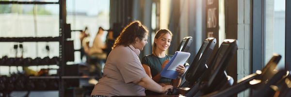 Woman smiling in gym, showcasing strength.