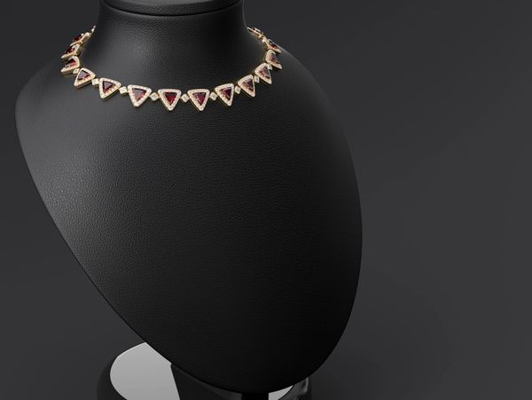 Elegant necklace with triangular red gemstones on a black display stand.