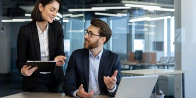 Two colleagues discussing work in a modern office setting.