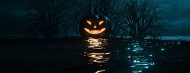 Glowing jack-o'-lantern with a sinister grin reflecting on dark water at night.