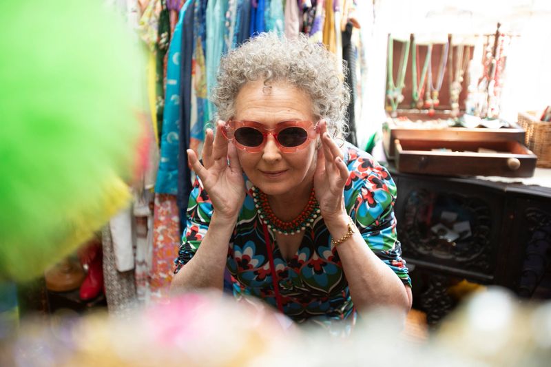 Senior woman shopping for vintage clothes and accessories in a store in Brighton, England.