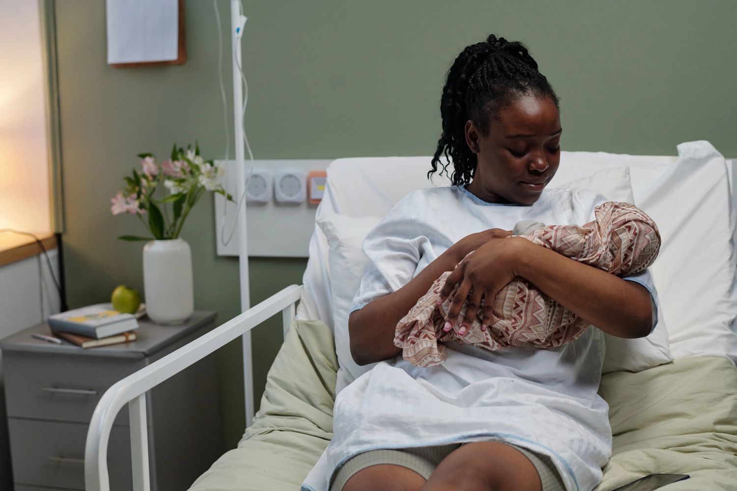 Mother lovingly cradling her newborn baby in a hospital bed.