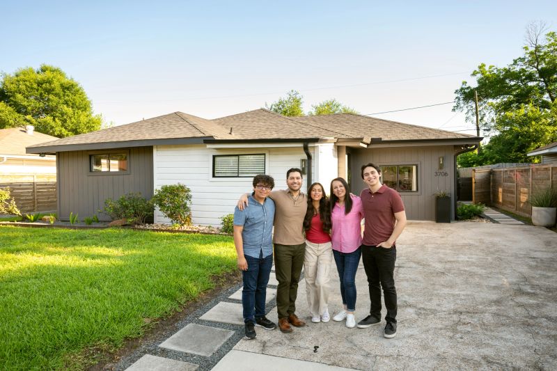 Family with three teens portrait in front their suburban home in Texas