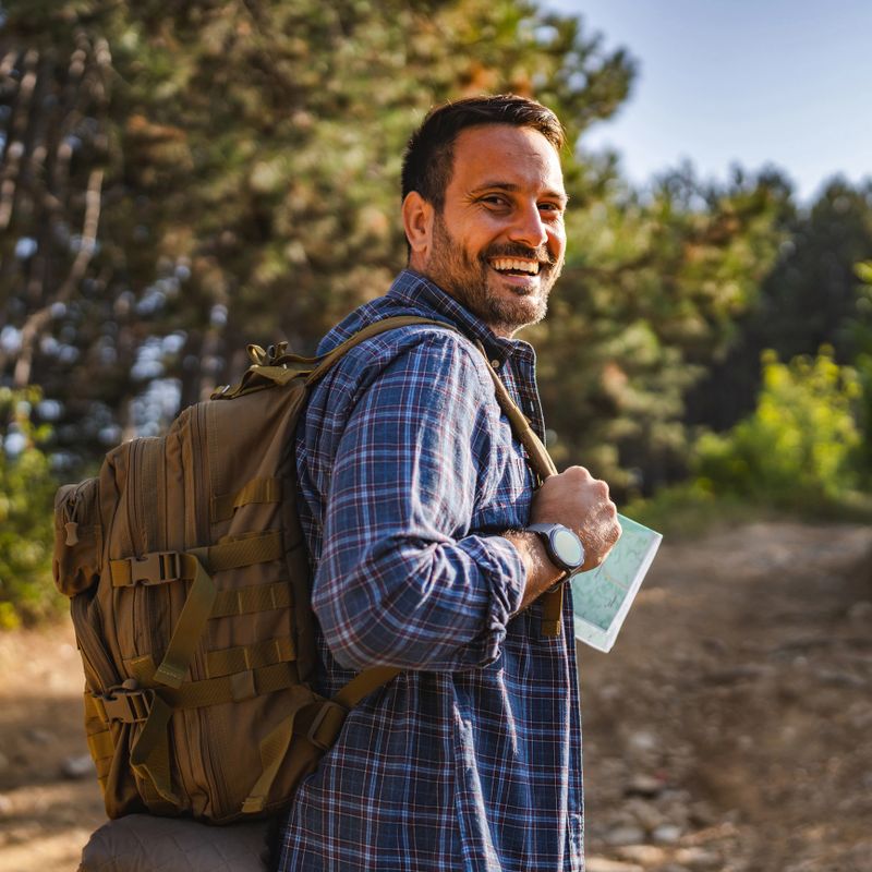 adult male camper with a backpack walking through the forest