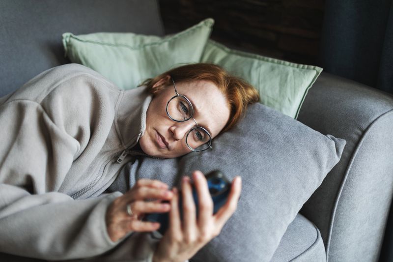 Mia adult woman lying in bed with mobile, sad and depressed, bad news