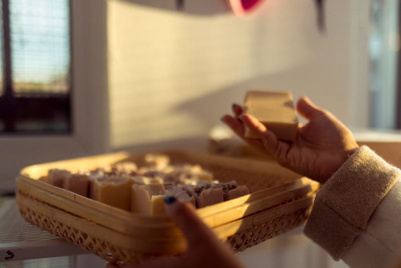 An unrecognizable woman arranges her handmade products. She arranges natural soaps side by side, before packaging and sending to customers. Close-up