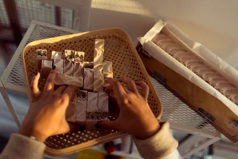 The unrecognizable small business owner takes the handmade natural soaps from the mold and arranges them, before packaging them and sending them to her customers