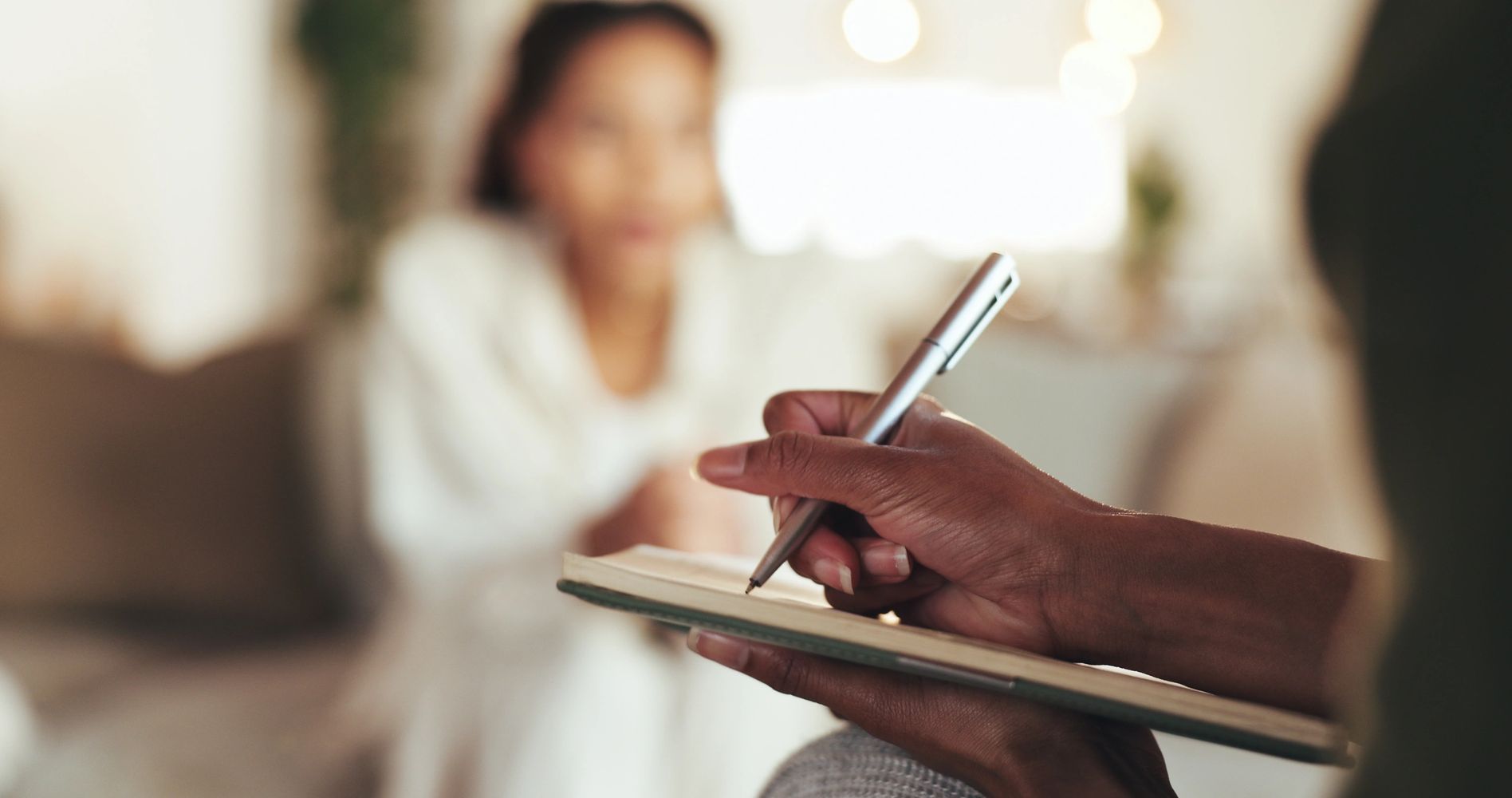 Close-up of a hand writing on a notepad during a conversation.