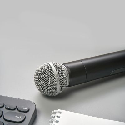 Microphone on a desk with a keyboard and notebook.
