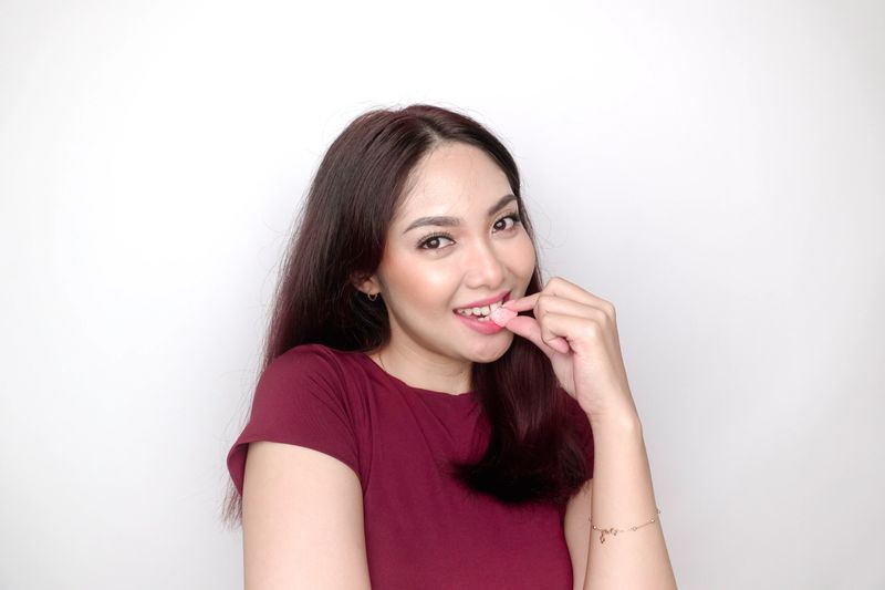 Image of a young Asian woman holding and looking at a jelly gummy.