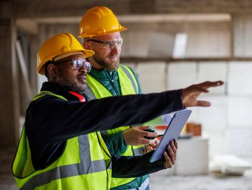 Construction workers reviewing plans at job site.