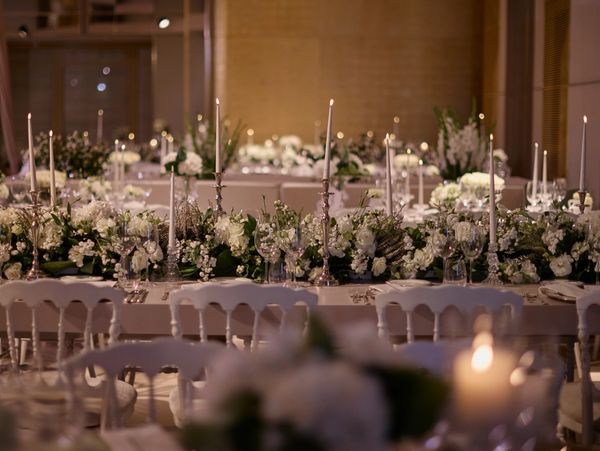 Elegant wedding reception table with white flowers and lit candles.