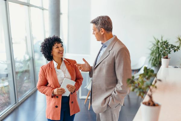A man being greeted by a smiling woman manager in the foyer