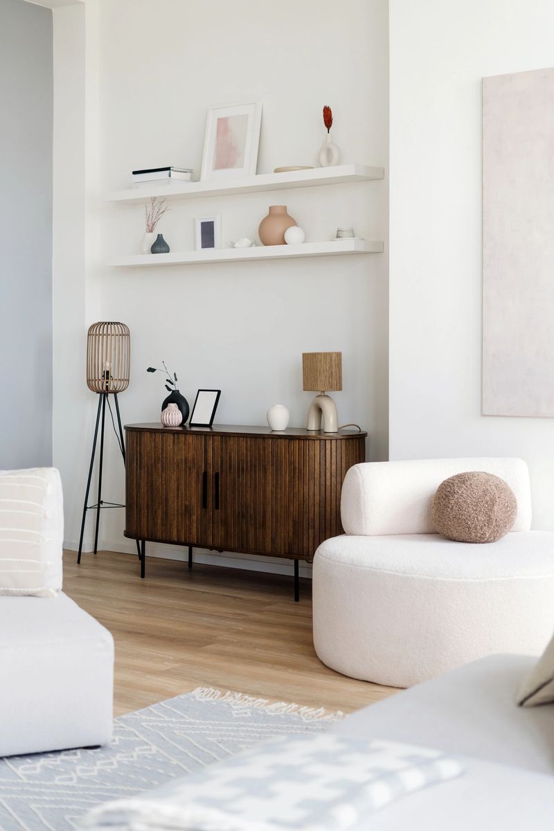 A cozy living room showcases a wooden sideboard paired with minimalist decor, comfortable soft furniture and warm lighting, creating a welcoming atmosphere at home