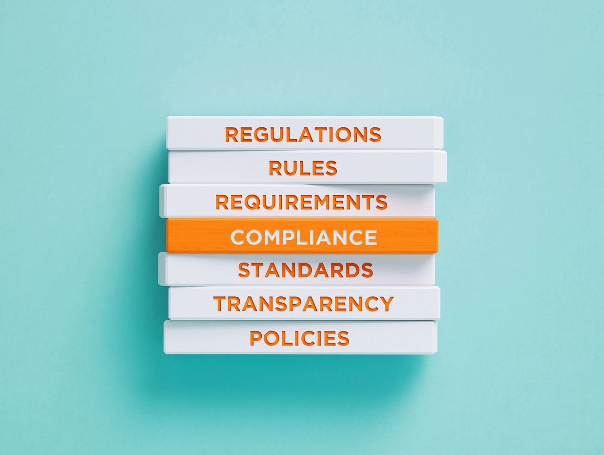Stack of books with titles on regulations, rules, and compliance.