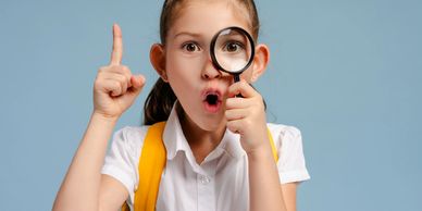 Curious girl with magnifying glass and raised finger.