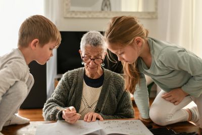 Elderly woman teaching kids at home.