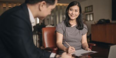 Woman smiling while taking notes during a meeting.