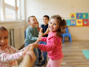 Children happily playing tug-of-war indoors, smiling and having fun.