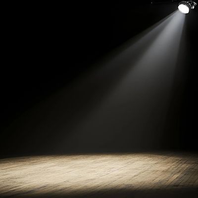 Bright spotlight on a wooden floor in darkness.
