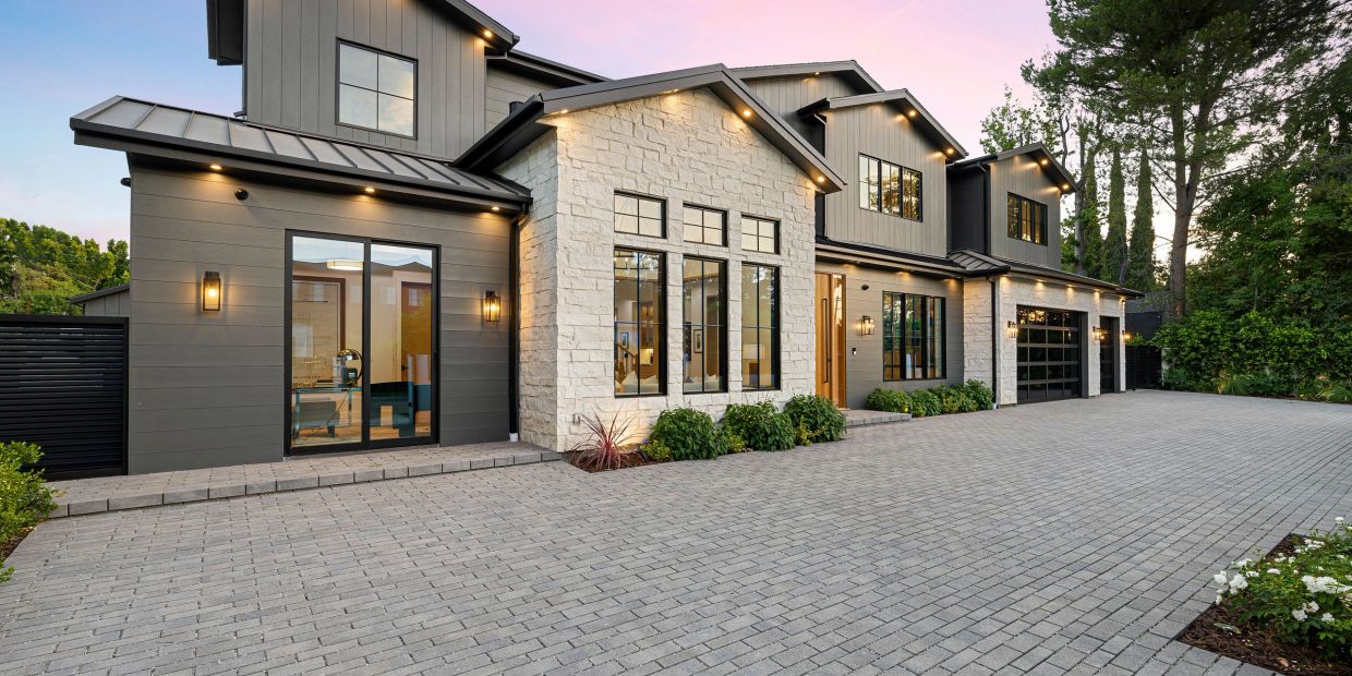 Modern two-story house with stone and dark panel exterior.