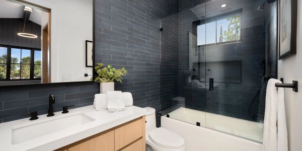 Modern bathroom with dark tiles and wooden vanity.