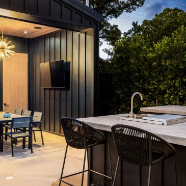 Modern outdoor patio with bar stools and dining table at dusk.