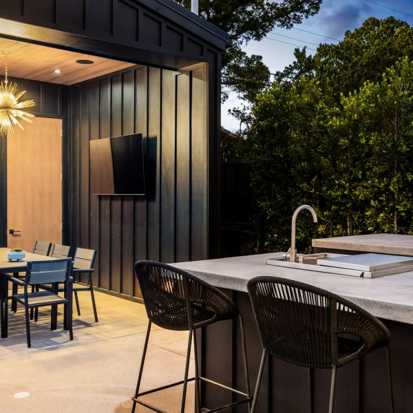 Modern outdoor patio with bar stools and dining table at dusk.